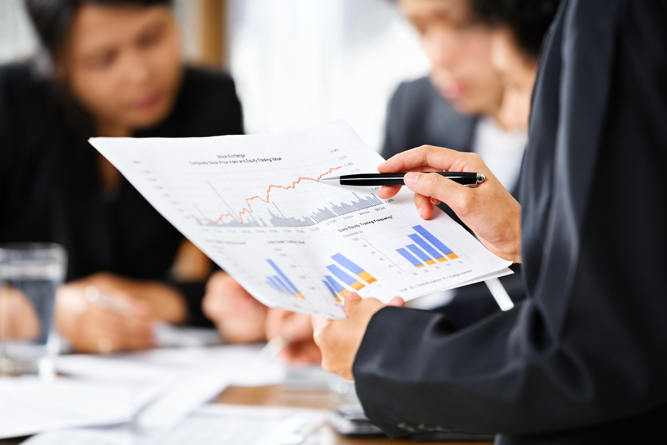 Business professional analyzing financial charts and graphs during a meeting, highlighting trends and data.
