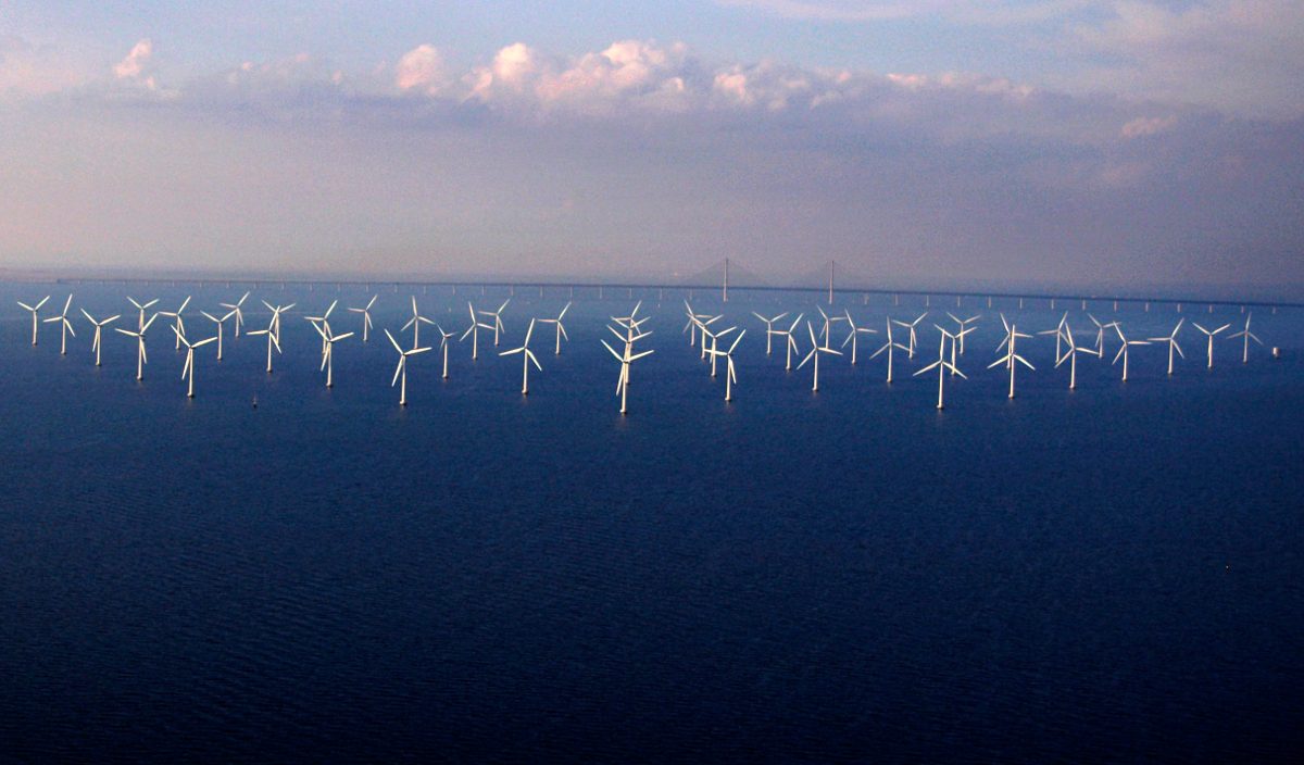 Offshore wind farm with multiple wind turbines in the sea under a cloudy sky, highlighting renewable energy production and sustainability.